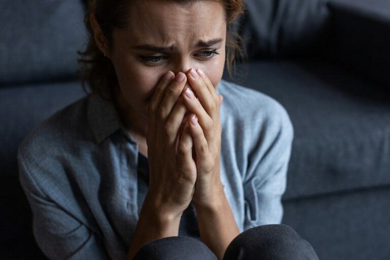 upset woman crying and covering face at home